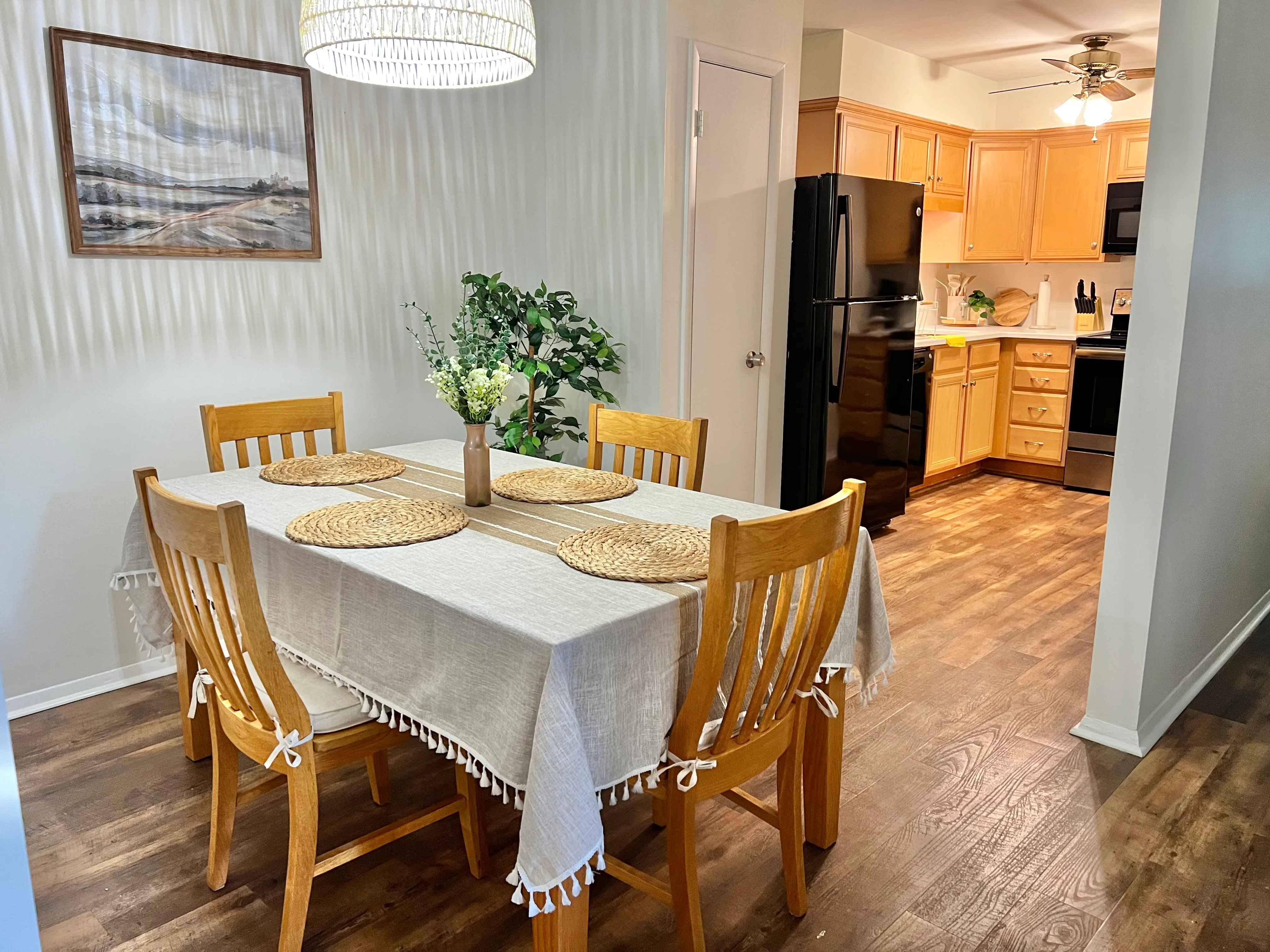 Dining table set for a meal, with the kitchen visible beyond