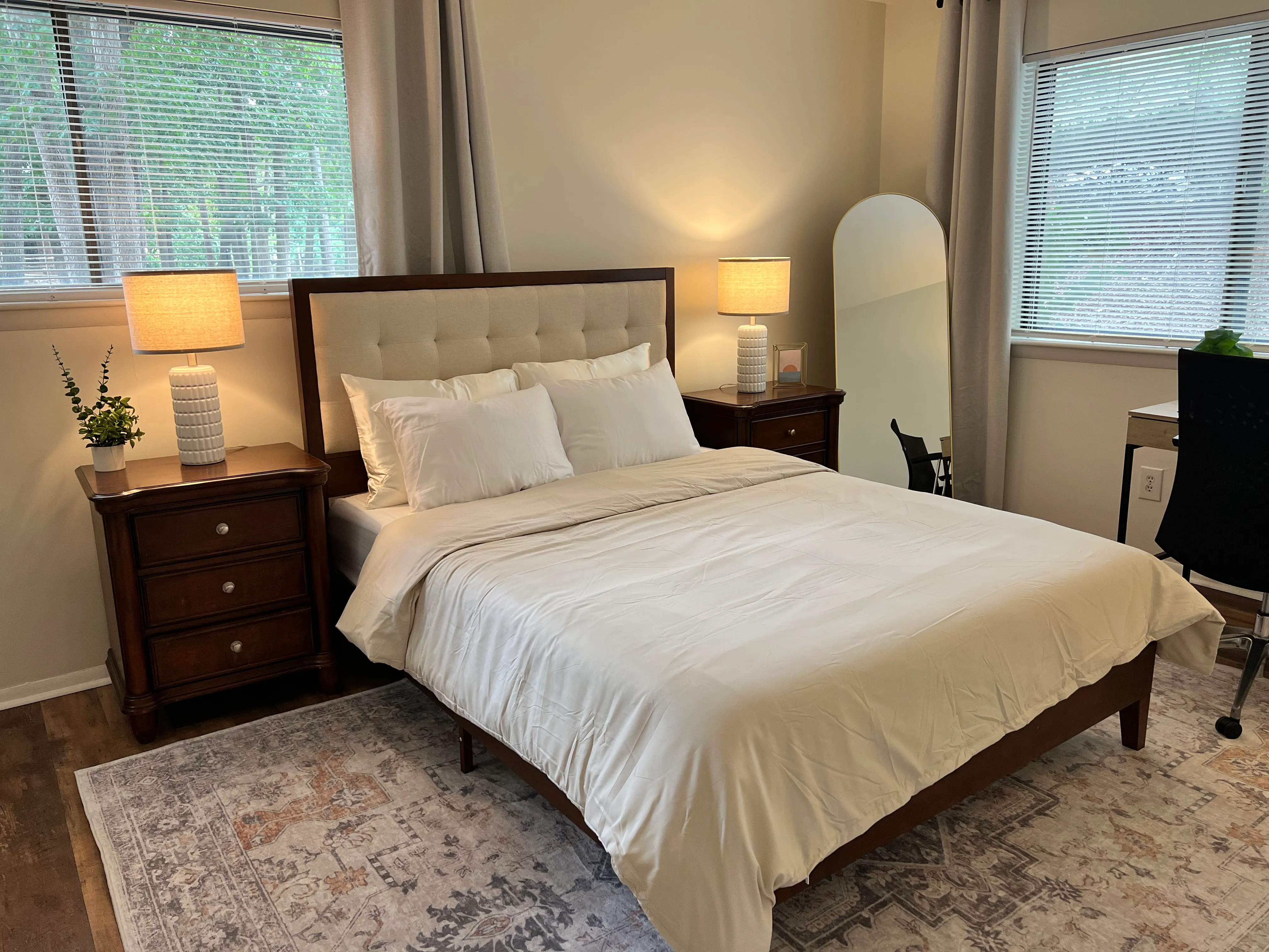 Primary bedroom with an upholstered bed, walnut nightstands, and warm lamps