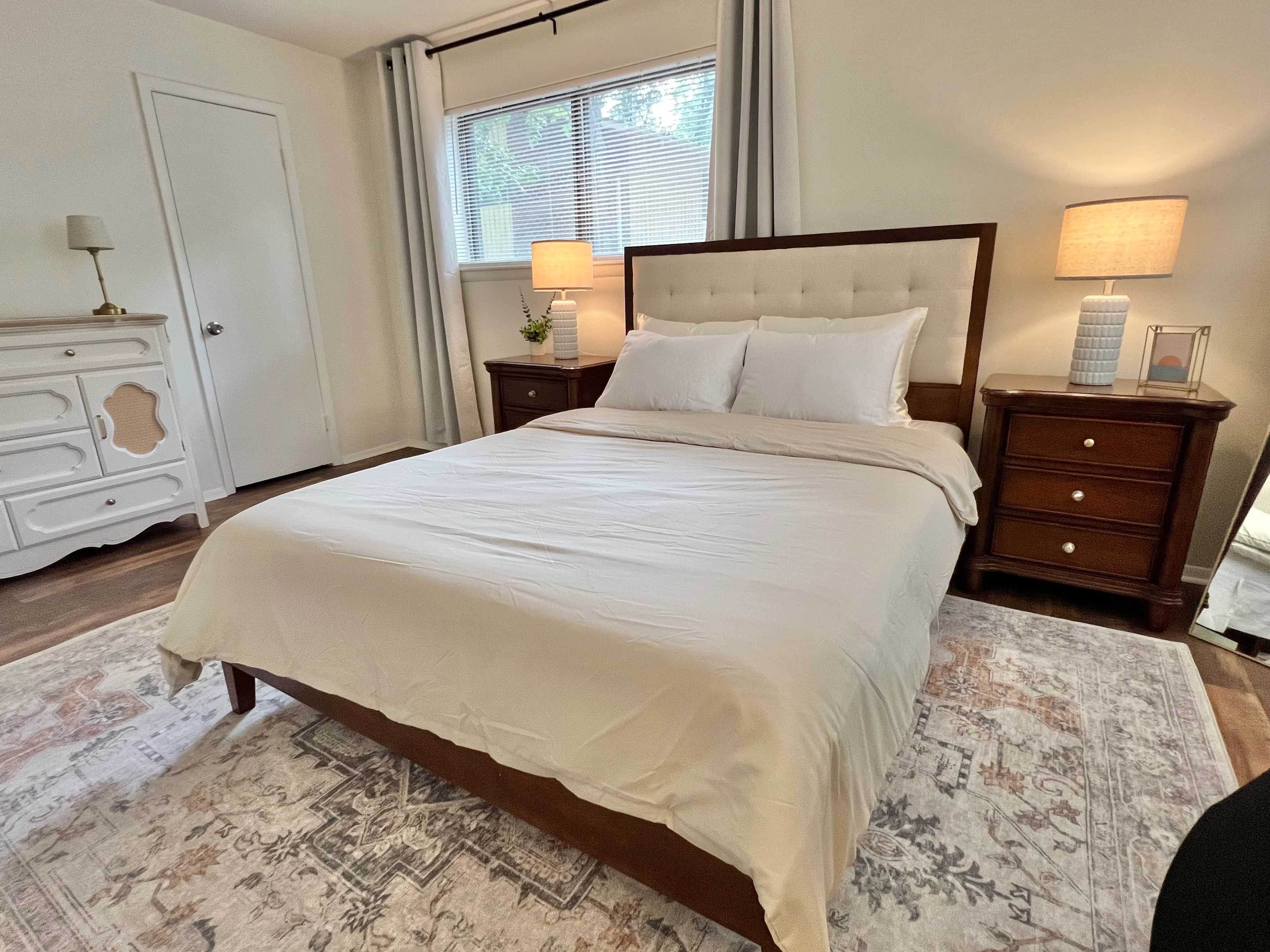 Primary bedroom wide view with dresser and layered rug