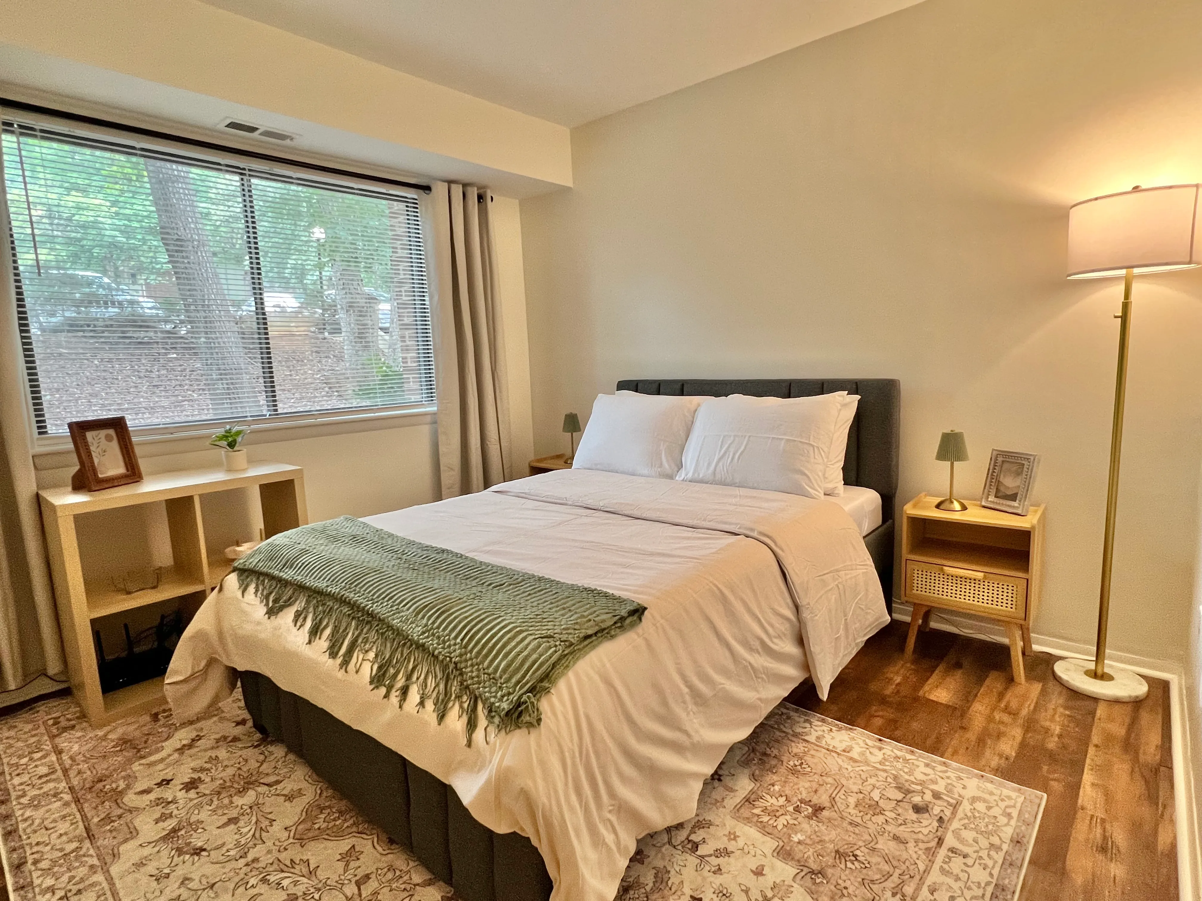 Second bedroom with a queen bed, sage throw, and natural-wood nightstands